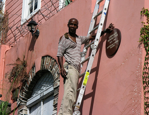 Workman placing plaque on Scott Street House